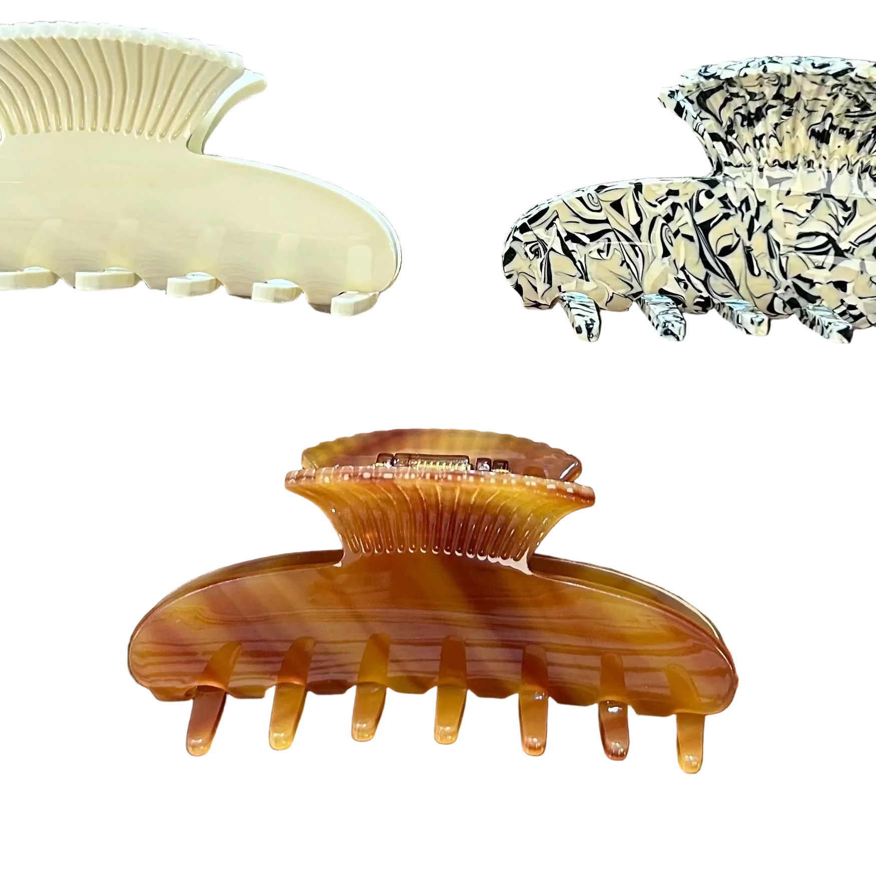 Three claw hair clips arranged on a textured brown surface: one cream-colored, one black and cream patterned, and one amber tortoiseshell.