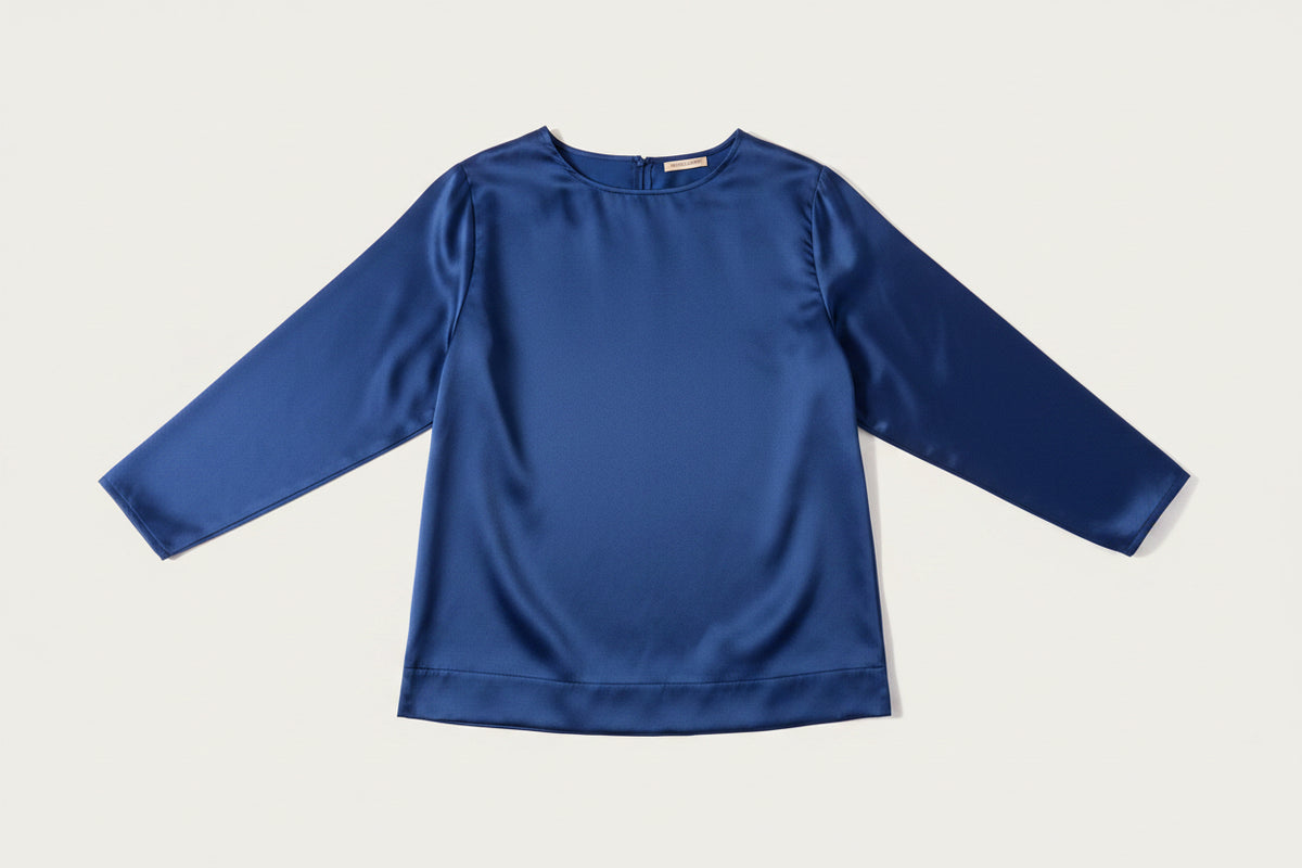 A black long-sleeve top with a crew neck, laid flat against a light beige background.