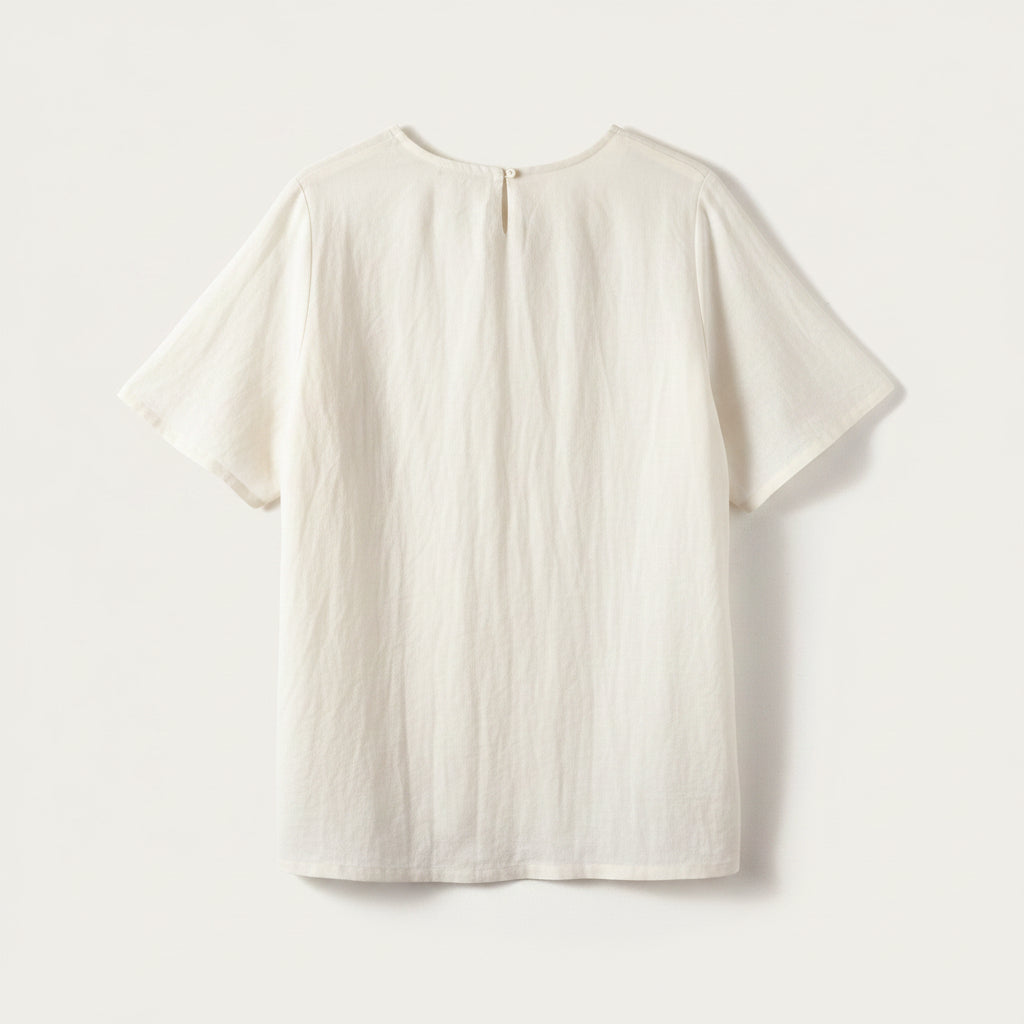 A light blue short-sleeve top with a relaxed, slightly wrinkled texture, shown from the back against a warm off-white background.