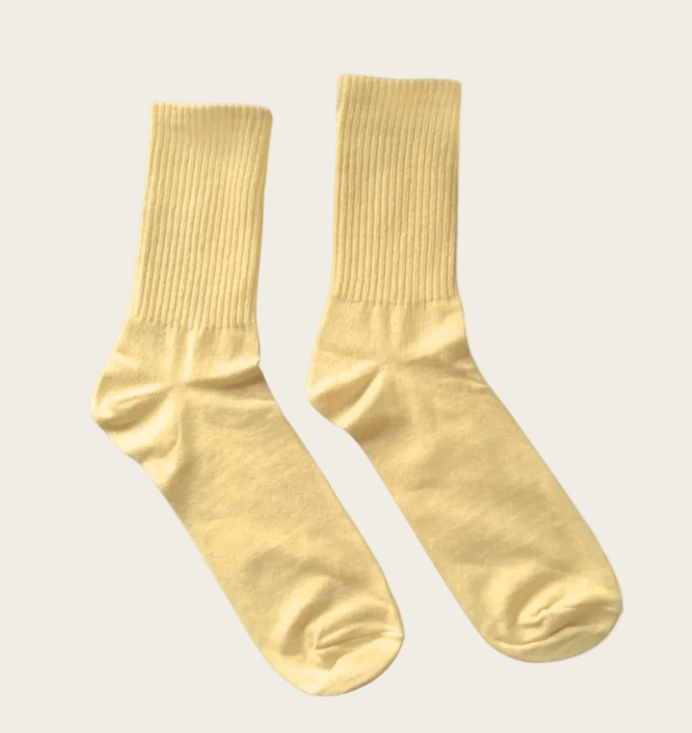 A pair of light yellow ribbed crew socks displayed against a solid white background.