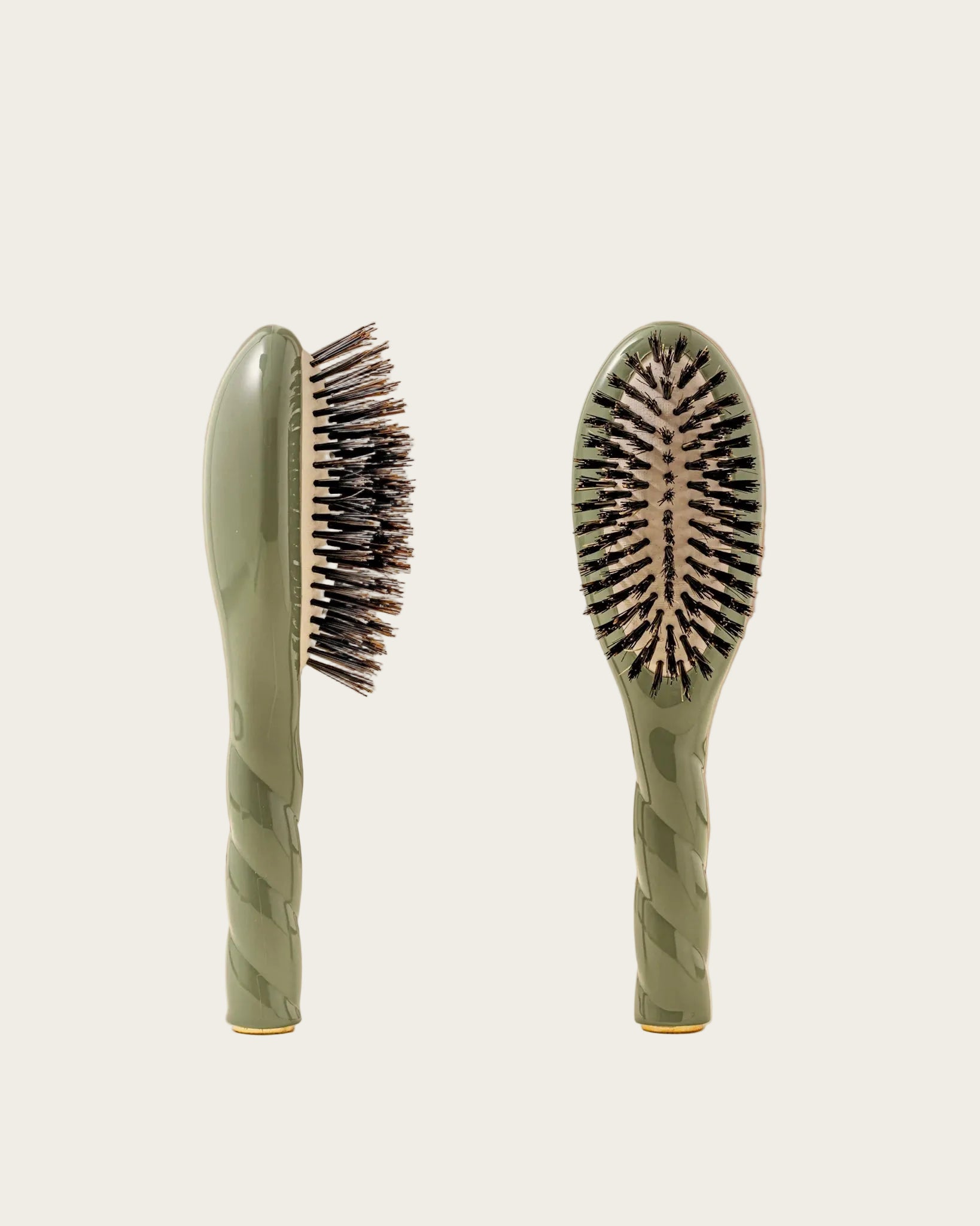 Two green hairbrushes with bristle heads on a beige background