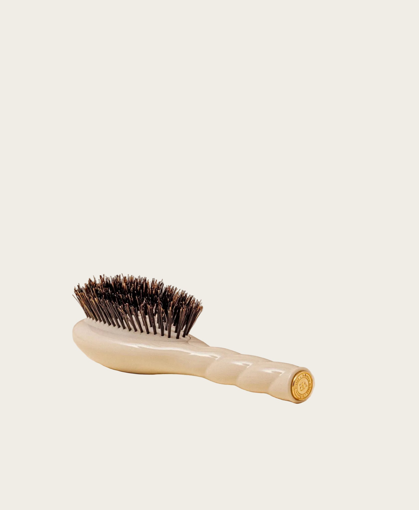 Hairbrush with a beige handle and bristles on a beige background