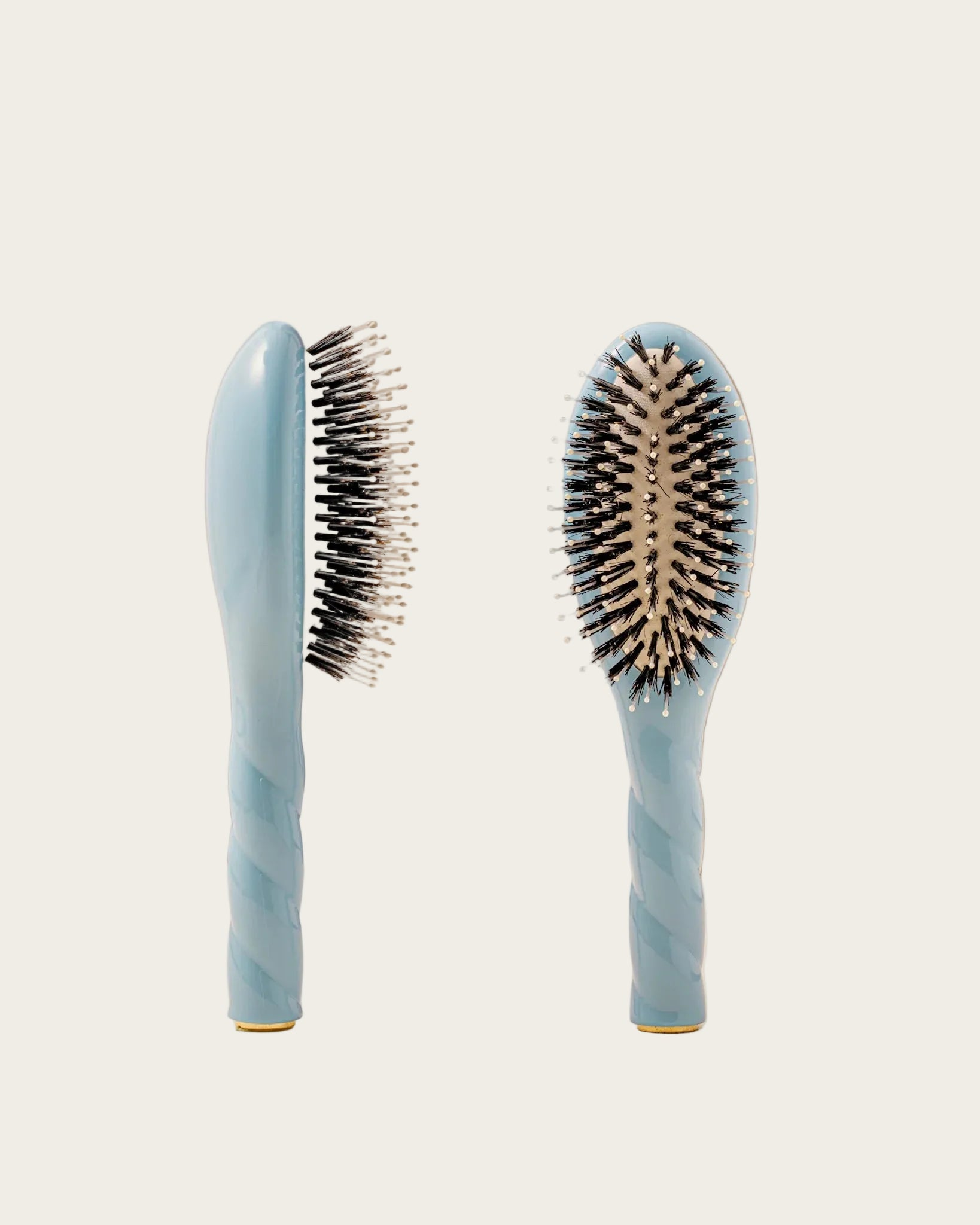 Two blue hairbrushes with black bristles on a beige background