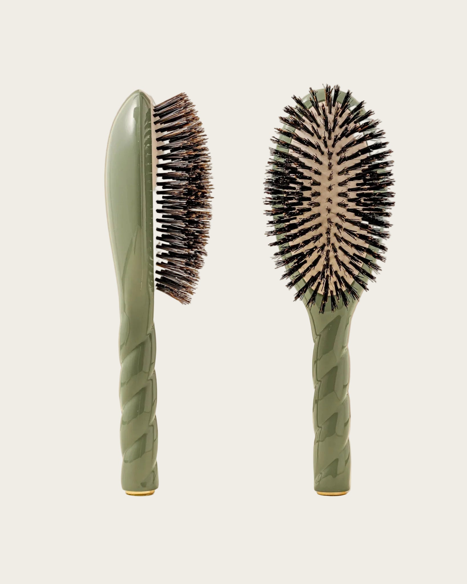 Two green hairbrushes with bristle heads on a beige background