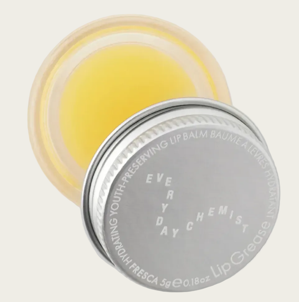 Yellow lip balm in a silver container with 'Every Day Chemist' branding on a light gray background