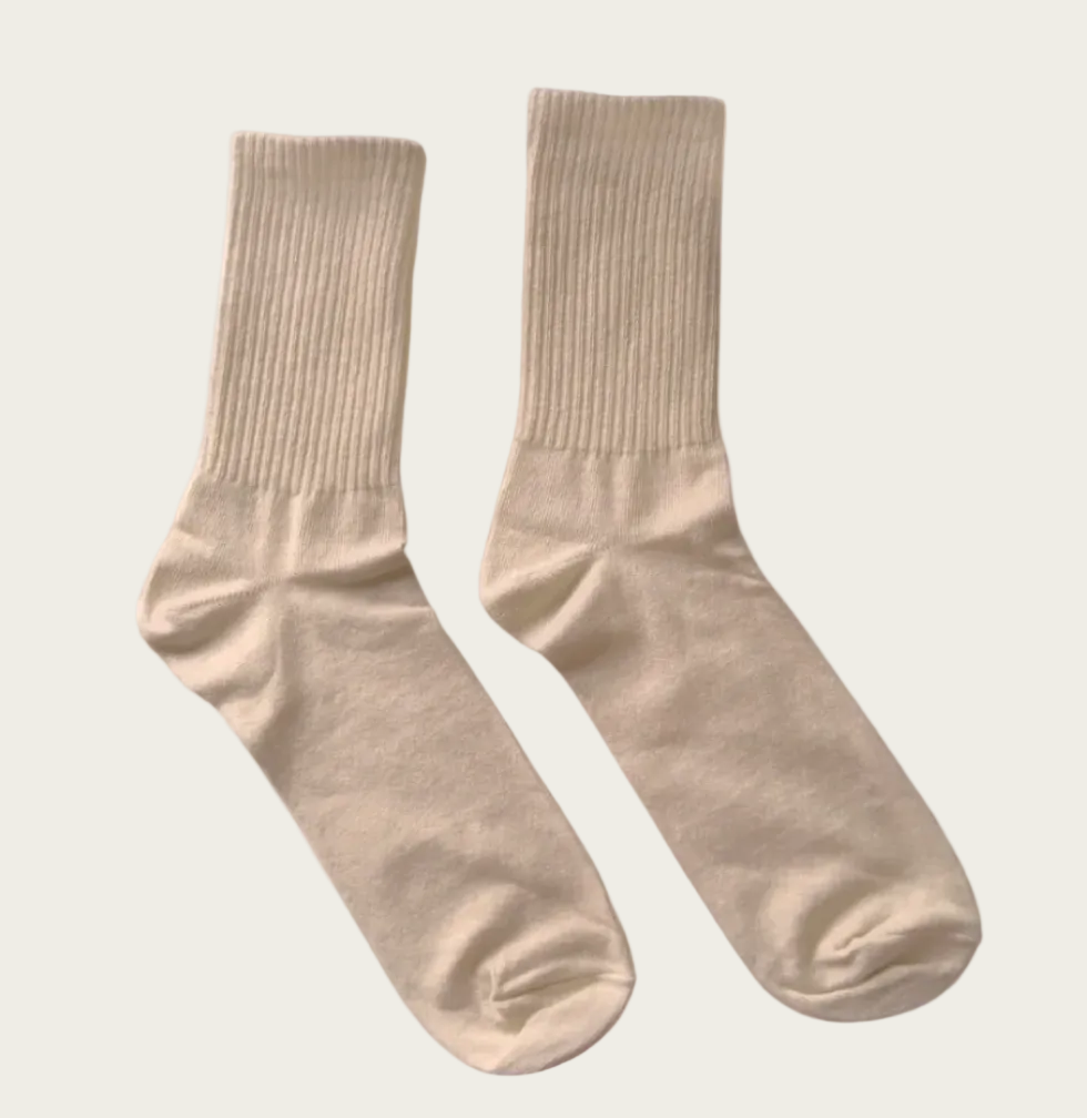 A pair of ribbed crew socks in a light beige or cream color, displayed against a solid white background.