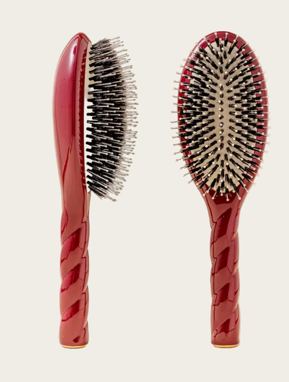 Two red hairbrushes with black bristles on a beige background
